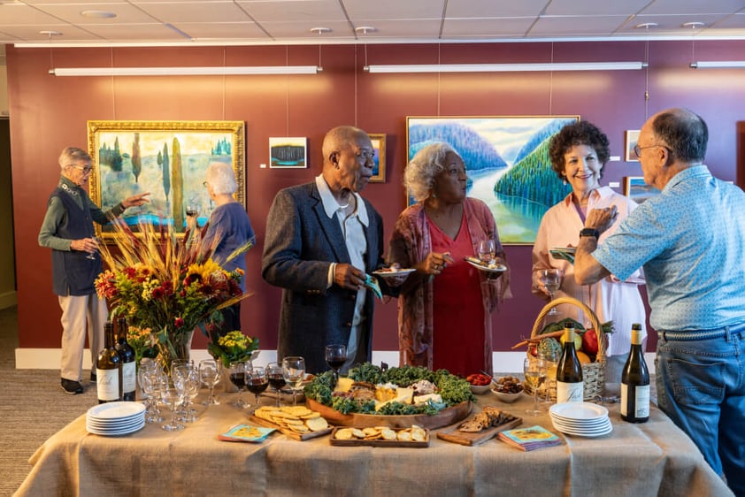 Group of seniors standing around food table in art gallery